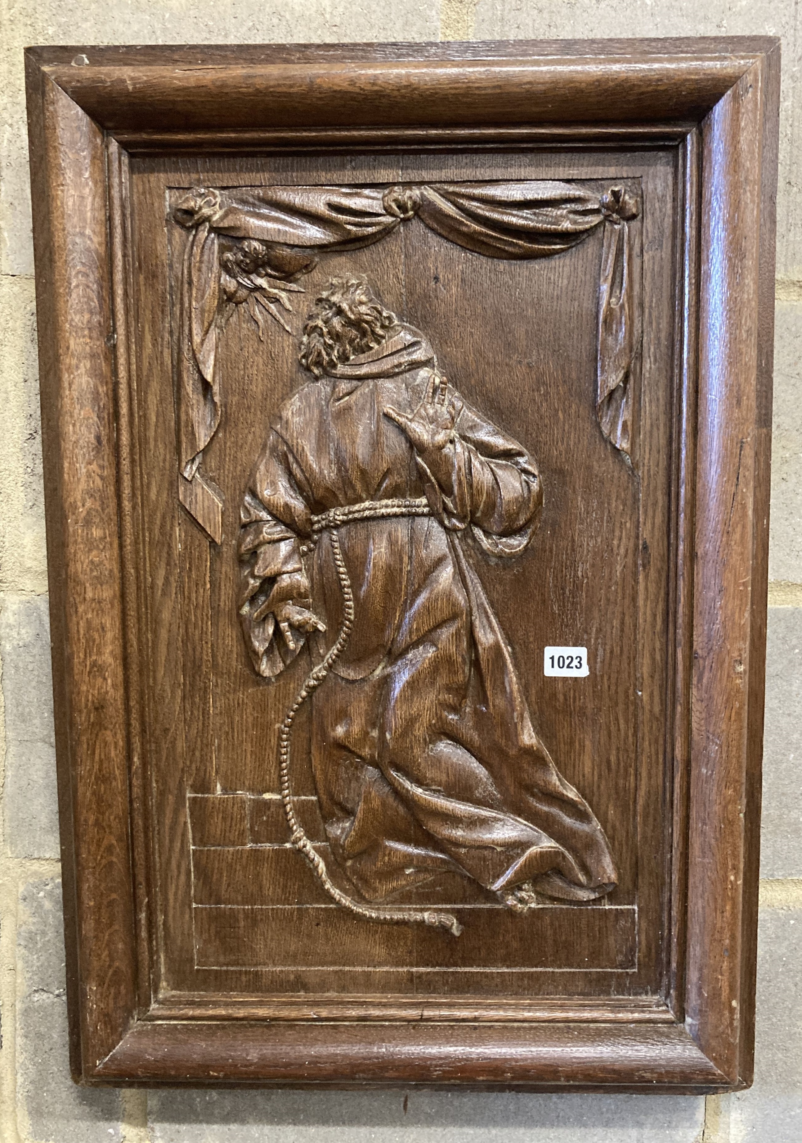 A rectangular carved oak wall panel depicting religious scene